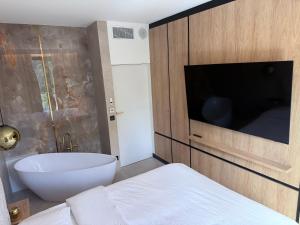 a bathroom with a tub and a tv and a bed at Apartament - VIDOK 110 in Olsztyn
