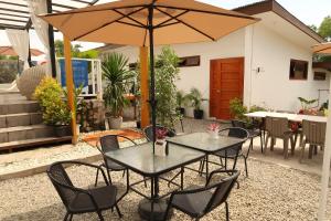 eine Terrasse mit Tischen, Stühlen und einem Sonnenschirm in der Unterkunft Balay Isabel in San Juan