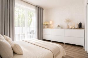 a white bedroom with a bed and a window at ALURE RESIDENCES 1 & 24h self check-in, free parking in front of the apartment building, new building, terrace, cafe with breakfast in the apartment building, next to the aqua park in Banská Bystrica