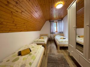 a room with three beds and a wooden ceiling at Chata Harmony in Ružomberok