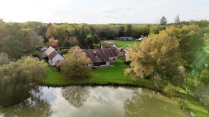 an aerial view of a house next to a pond at Ferme Boisquillon in Marcilly-en-Gault
