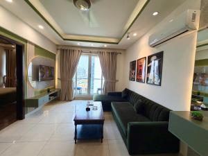 a living room with a green couch and a table at Designer One Bedroom Apartment With Balcony & Mountain Views Opposite Centaurus Mall ISB in Islamabad
