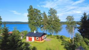 a small red house on a lawn next to a lake at Schwedenhaus am See in Storfors