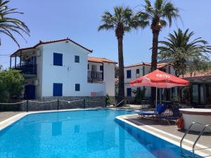 a swimming pool with a red umbrella and a house at Anaxos Garden in Anaxos