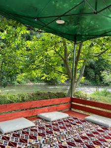 two beds on a porch with a green umbrella at Apartman Elma in Jajce