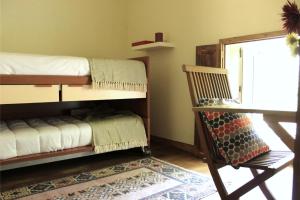 a bedroom with a bunk bed and a chair and a desk at Casa Moinho da Levada - Refúgio à beira do rio Coura in Paredes de Coura