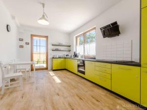 a kitchen with yellow cabinets and a table in it at Pokoje u Emilii in Mikołajki