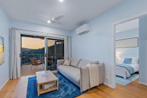 a living room with a couch and a balcony at Seabreeze Lookout Azul in Airlie Beach
