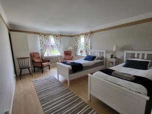 a bedroom with two beds and a chair at Smedstugan in Norrköping
