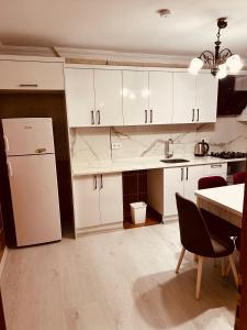 a kitchen with white cabinets and a white refrigerator at ZEREN APART 2 CENTRUM in Uzungöl
