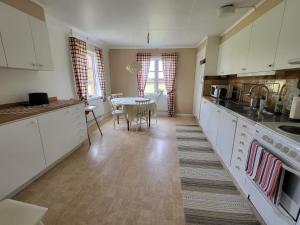 a kitchen with white cabinets and a table in it at Smedstugan in Norrköping