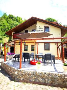 a patio with tables and an umbrella in front of a building at Villa Slnava in Banka