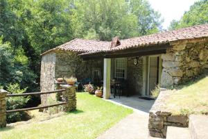 a stone house with a porch and a patio at Casa Moinho da Levada - Refúgio à beira do rio Coura in Paredes de Coura