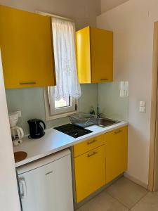 a small kitchen with yellow cabinets and a sink at Glikis Ear Apartments in Gliki