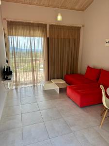 a living room with a red couch and a large window at Glikis Ear Apartments in Gliki