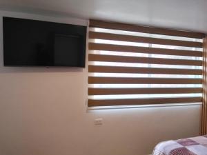 a bedroom with a window with a flat screen tv at Suite La Frontera in Tulcán +3 photos