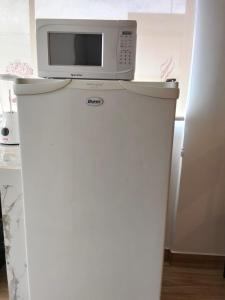 a microwave on top of a refrigerator in a kitchen at Suite La Frontera in Tulcán