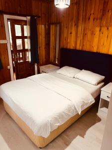 a bedroom with a large white bed with wooden walls at ZEREN APART 2 CENTRUM in Uzungöl
