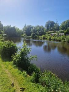 a river with trees in the background and a field at Chalet 85 in Caeathro +4 photos