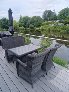 a wooden deck with a table and chairs next to a river at Chalet 85 in Caeathro
