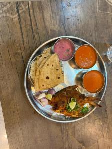 a plate of food with meat and dips on a table at SH Guest House Malvan in Malvan