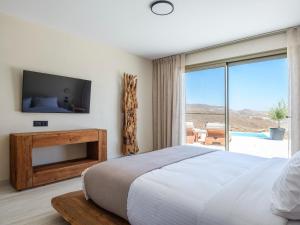 a bedroom with a large bed and a tv at Vinara Luxury Suites Mykonos in Mykonos +55 photos