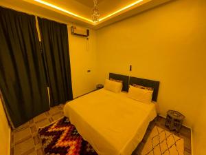 a bedroom with a bed with white sheets and a window at Maison-Lala Takerkoust et agafay in Lalla Takerkoust