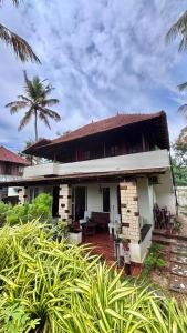 a house with a palm tree in front of it at Emmanuals beach house in Alleppey