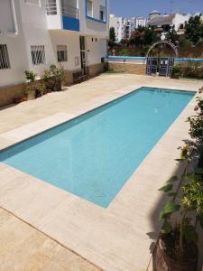 a swimming pool in front of a building at Olas Appartement Escapade Méditerranéenne à Martil Confort & Proximité Plage in Martil