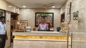a man standing behind a counter in a temple at Raya's Inn in Kumbakonam