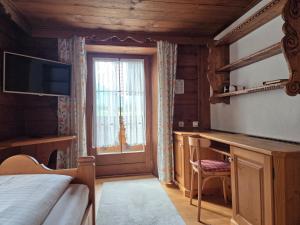a bedroom with a bed and a window and a desk at Pension Monteneu in Bartholomäberg