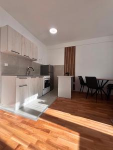 a kitchen with white cabinets and a table and chairs at Apartman ART Foca in Foča