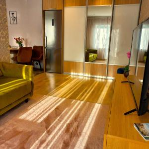 a living room with a yellow couch and a mirror at Yasmin Apartment in Pärnu