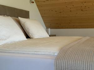 a bed with white sheets and pillows in a room at Osada Iwiec-Karpaty w Borach Tucholskich in Iwiec