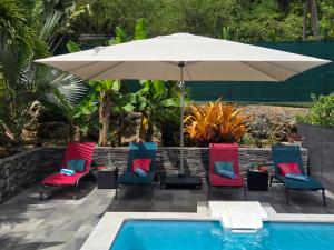 a patio with chairs and an umbrella next to a pool at Villa Fleur de Lys MAE in Morne-à-lʼEau
