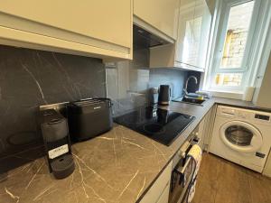 a kitchen with a stove top oven next to a washing machine at Dunes Apartment Troon in Troon