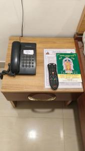 a desk with a phone and a book on it at Raya's Inn in Kumbakonam