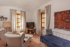 a living room with a bed and a tv at Köveskál Vendégház in Köveskál