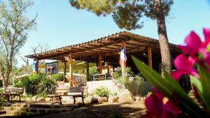 a wooden pavilion with benches and a flag at Campo Di Mare in Porto-Vecchio