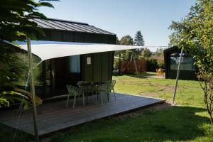 a deck with a table and chairs under a white umbrella at Wellnester Tiny Houses in Losheim am See in Losheim