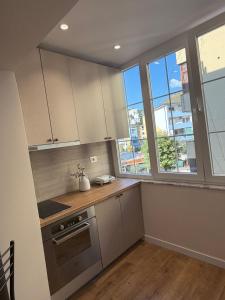 a kitchen with white cabinets and a stove and windows at Koko Pepito apartment in Lezhë