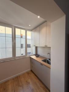 a kitchen with white cabinets and a sink and windows at Koko Pepito apartment in Lezhë