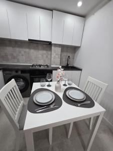 a white table with two chairs and a white kitchen at Colins Premium Apartments in Giurgiu