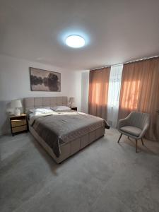 a bedroom with a large bed and a chair at Colins Premium Apartments in Giurgiu