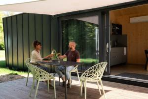 a man and woman sitting at a table outside a house at Wellnester Tiny Houses in Losheim am See in Losheim
