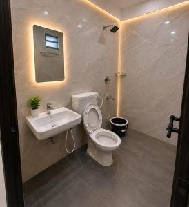 a bathroom with a white toilet and a sink at Levora Suits in Kottayam
