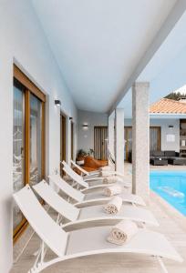 a row of white lounge chairs next to a swimming pool at Casa Fregim in Amarante