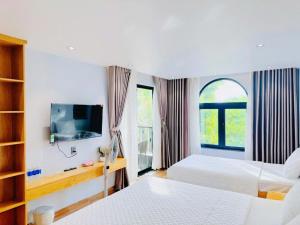 a hotel room with two beds and a tv at Bay Homestay in Cam Lâm