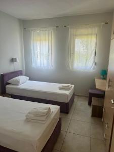 a bedroom with two beds and two windows at Glikis ear apartments in Gliki