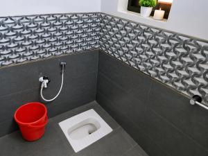 a bathroom with a toilet with a red bucket at VBH Tourist Homestay in Guruvāyūr